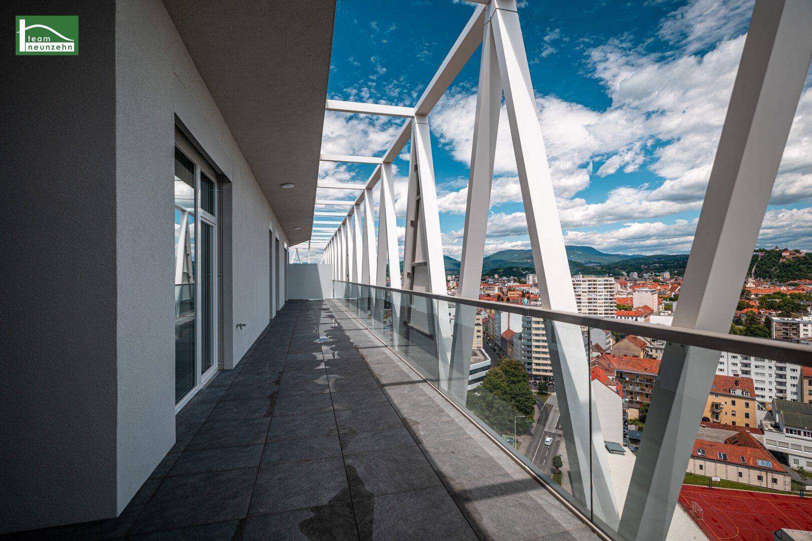 Lange, moderne Terrasse mit Glasgeländer und weitem Blick über die Stadt.