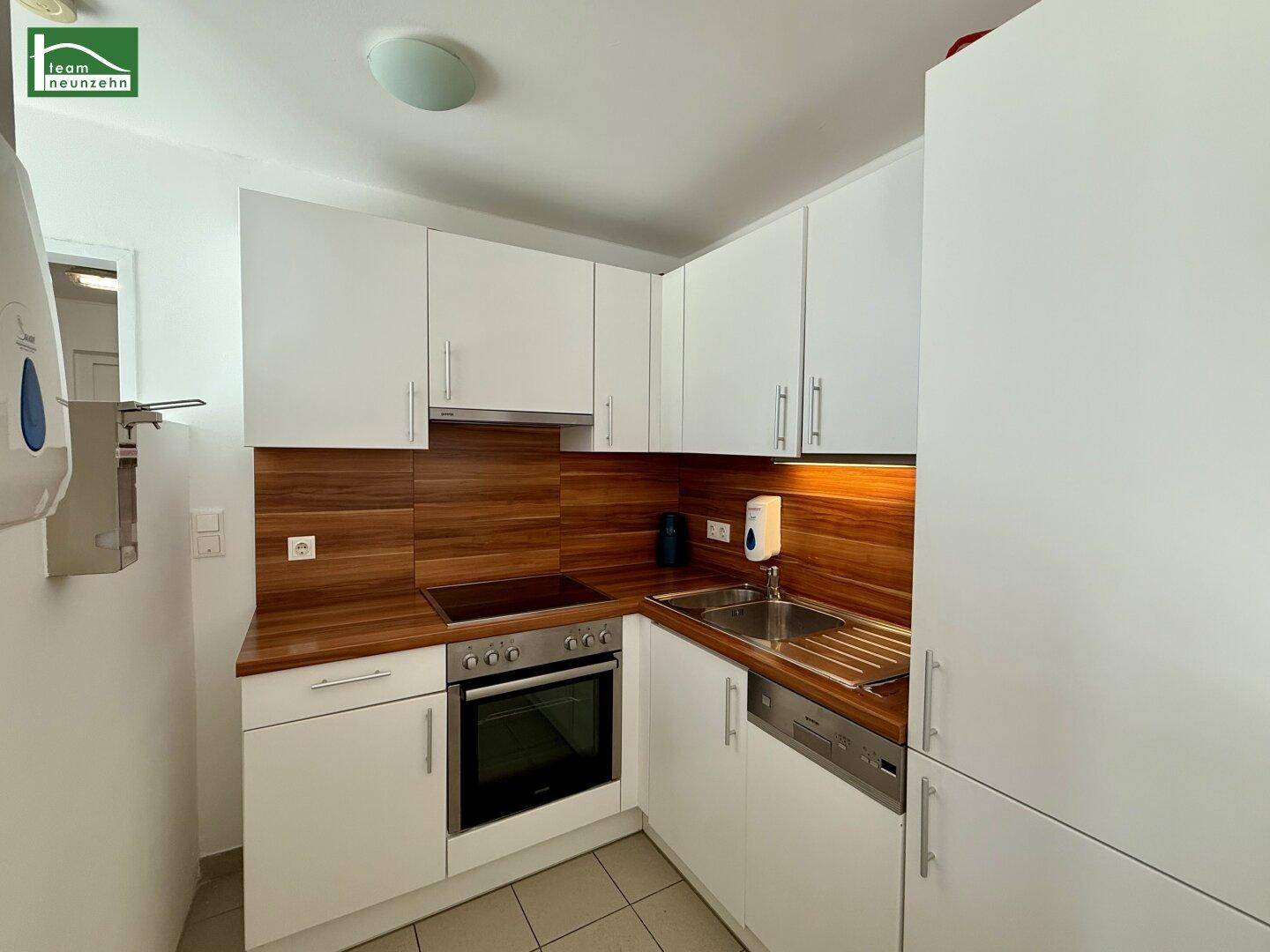 Funktionale Küche mit weißen Schränken, Holz-Arbeitsplatten und integrierten Geräten.