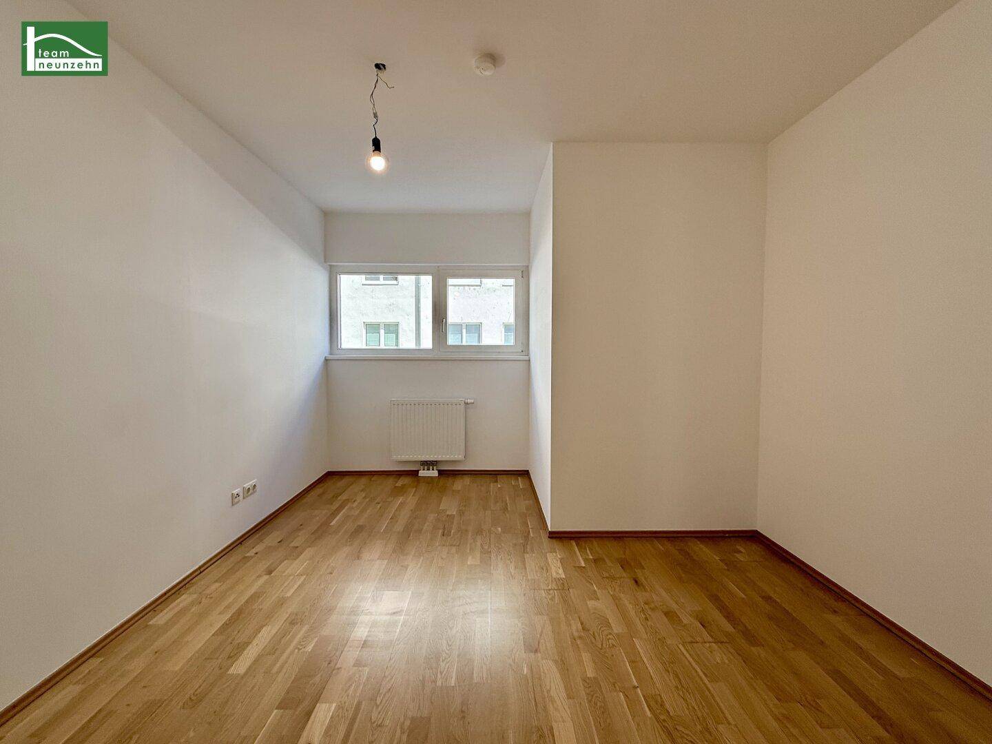Helles Zimmer mit Parkettboden und einem Fenster, ideal als Schlaf- oder Arbeitszimmer.
