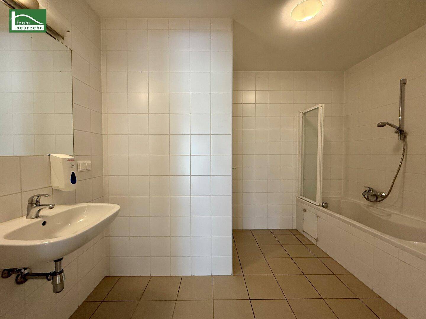 Badezimmer mit Badewanne, Duschabtrennung, Waschbecken und weißen Fliesen.
