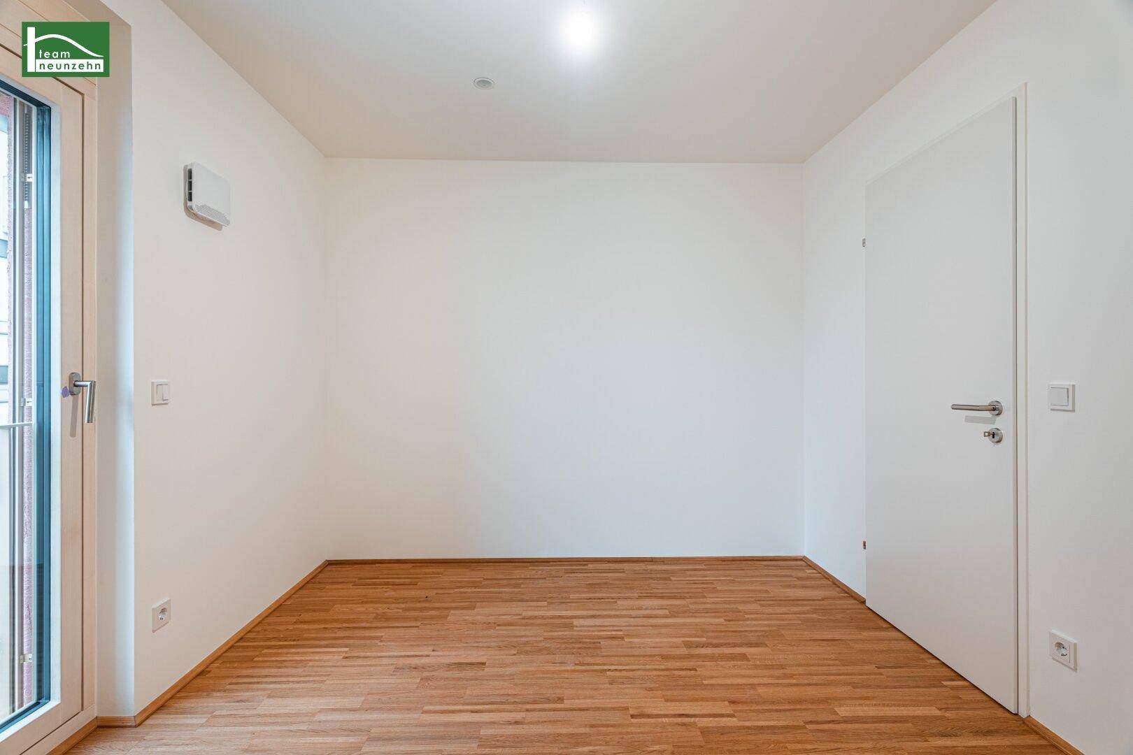 Helles Schlafzimmer mit Parkettboden und Fenstertür zu einem französischen Balkon.
