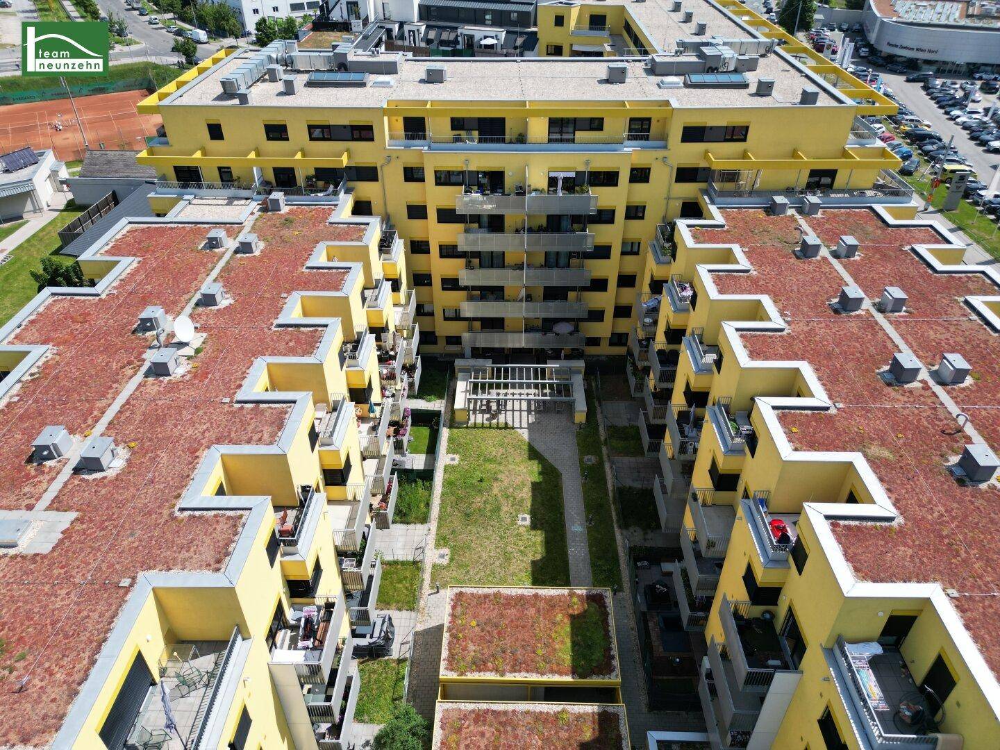 Luftaufnahme eines großen Wohnkomplexes mit gelben Fassaden und begrünten Dächern.