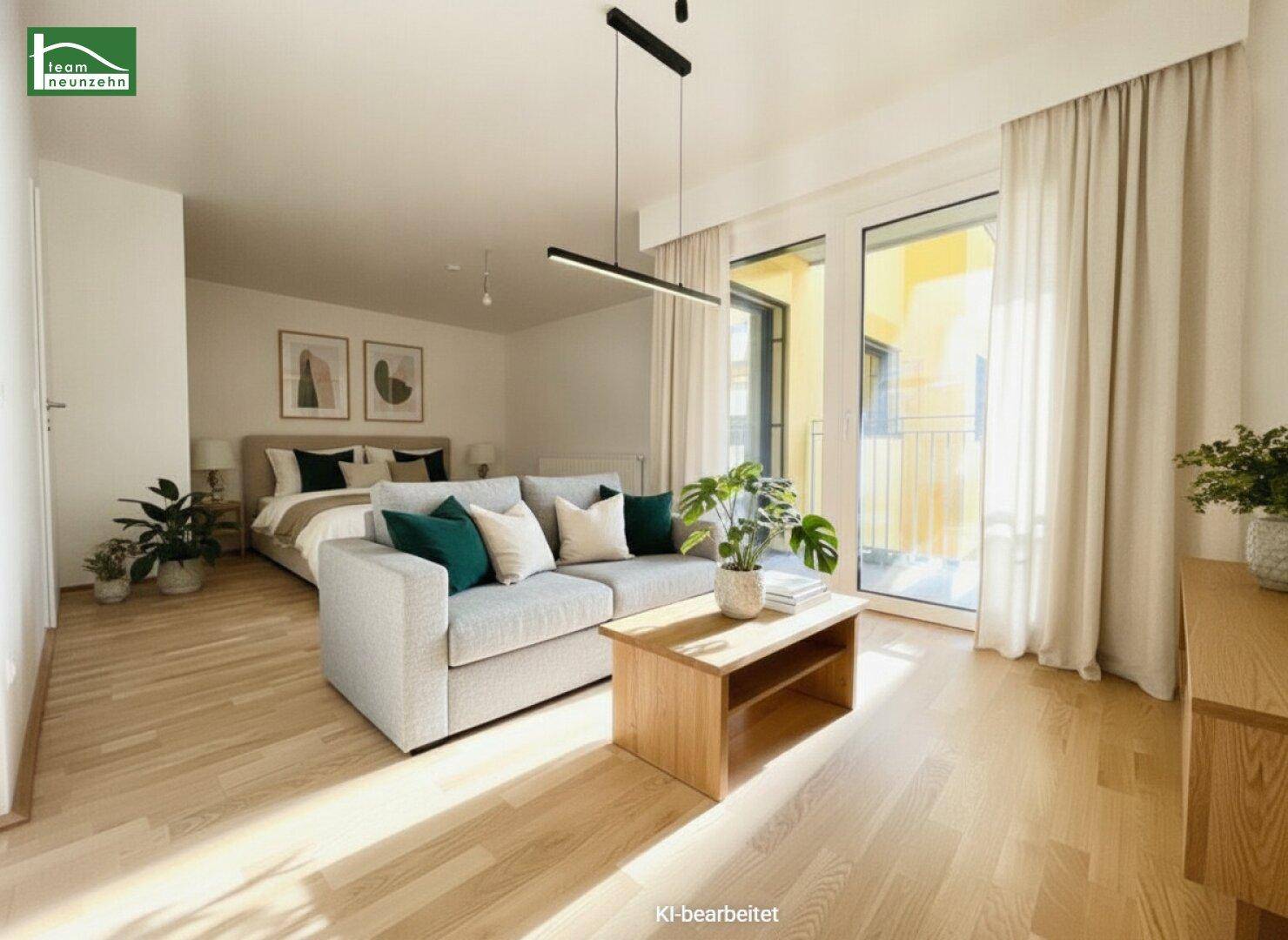 Möbliertes Wohnzimmer mit Sofa, Bett im Hintergrund und Zugang zum Balkon.