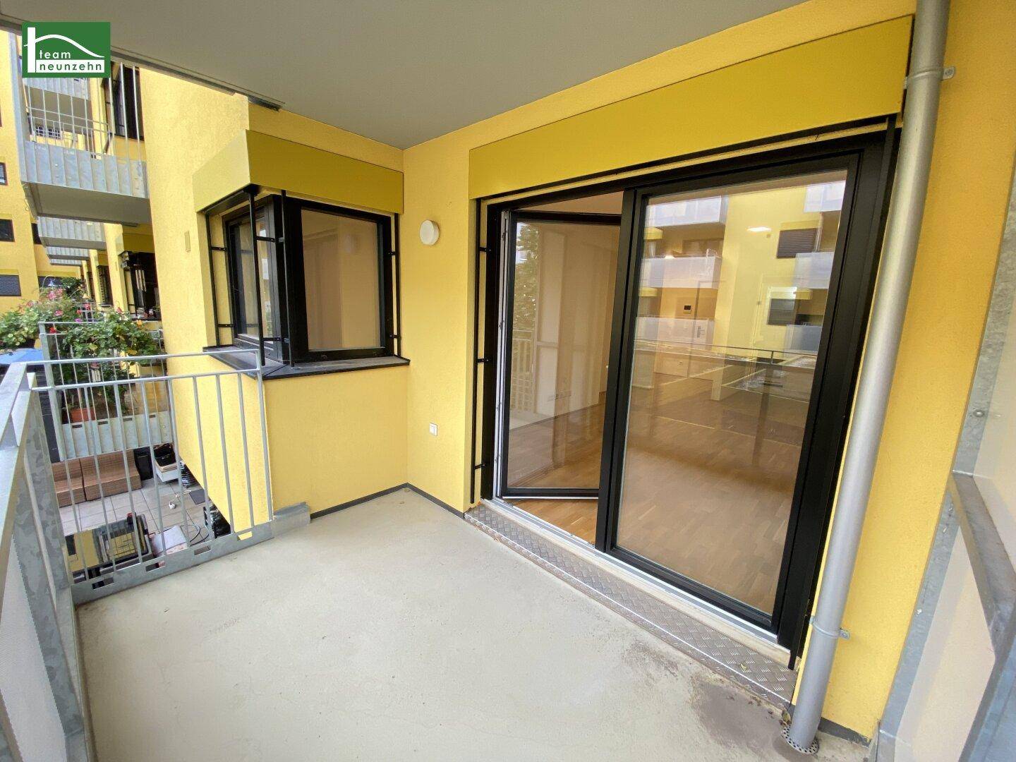 Heller Balkon mit Metallgeländer und Blick auf den Innenhof des Gebäudes.