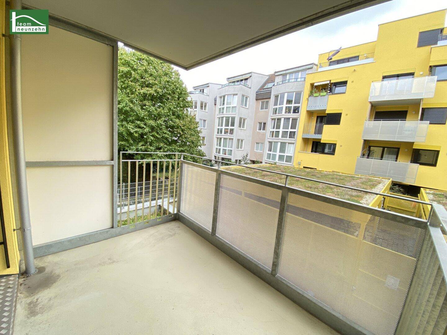 Balkon mit Blick auf die umliegenden Gebäude und grüne Dächer.