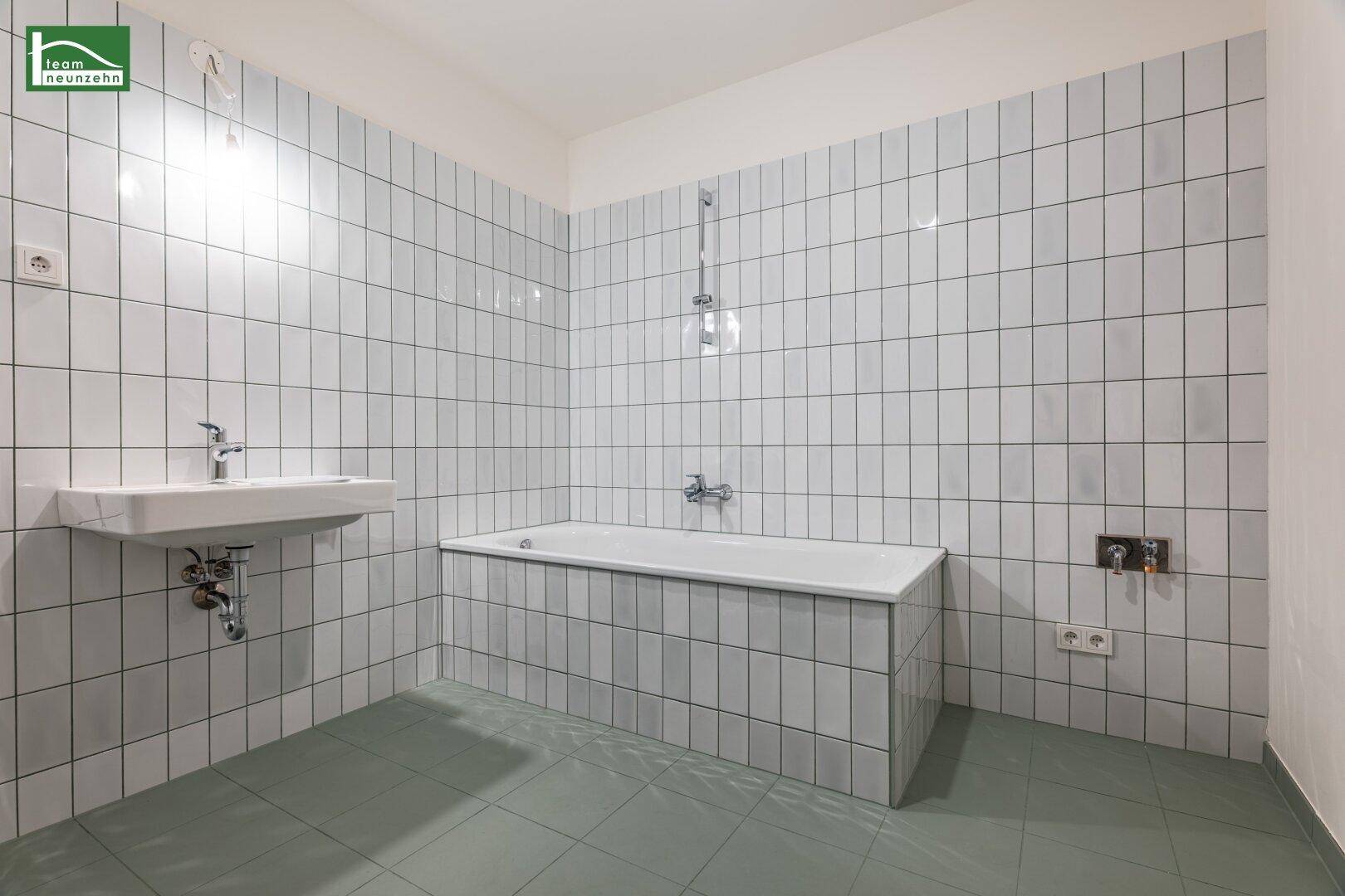 Helles Badezimmer mit weißen Wandfliesen, Badewanne und Waschbecken, bereit zur Nutzung.