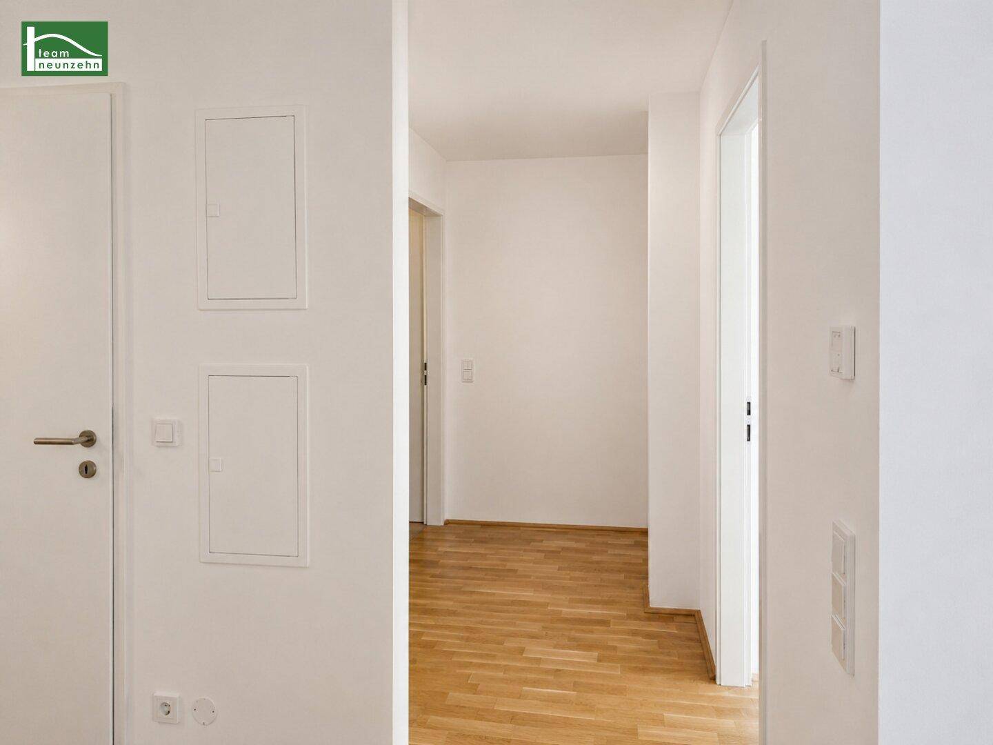 Heller Flur mit Holzboden und mehreren Türen, die zu den Zimmern führen.