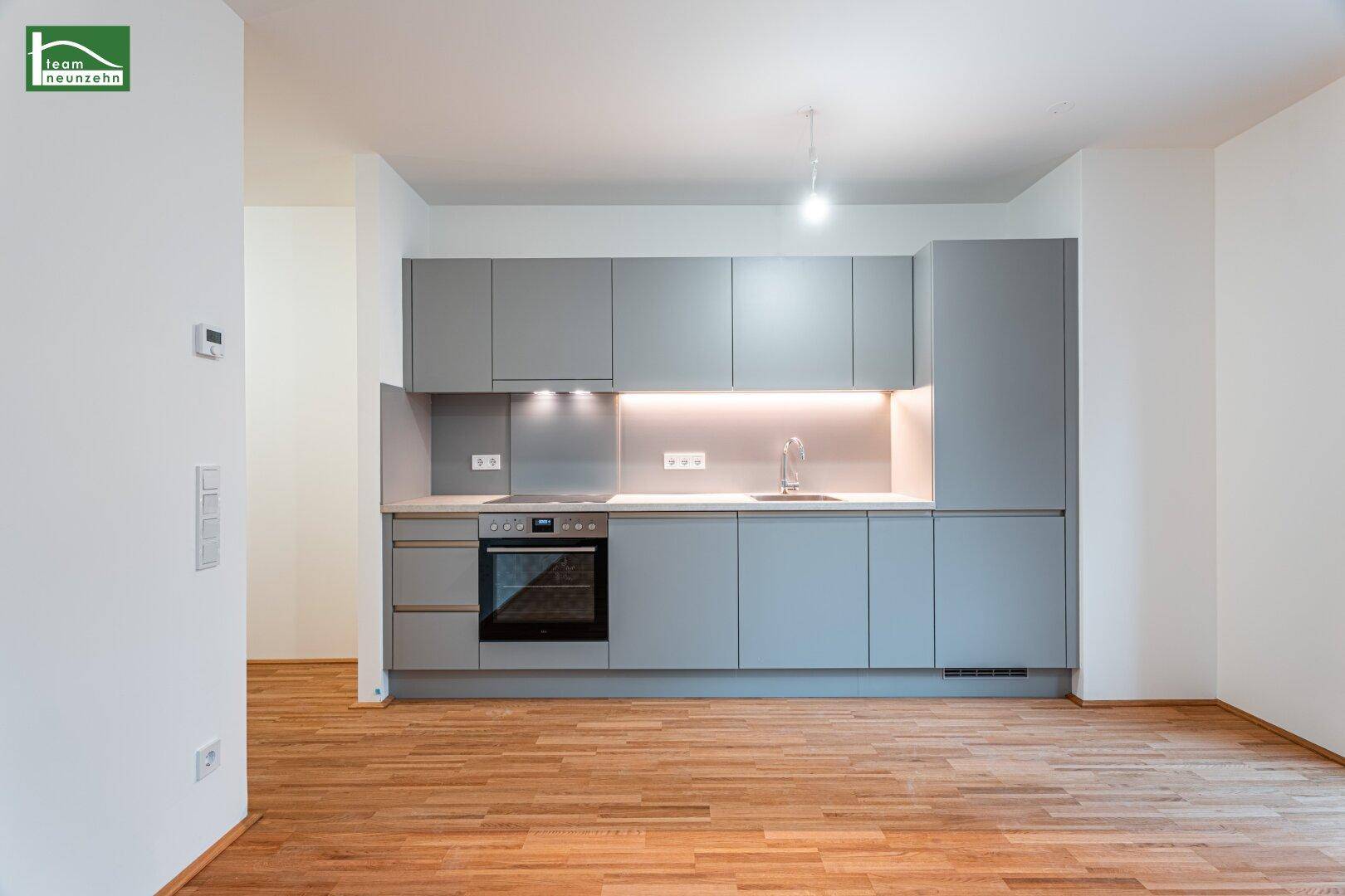 Moderne Einbauküche in Grau mit integrierten Geräten und Arbeitsplatte, bereit zur Nutzung.