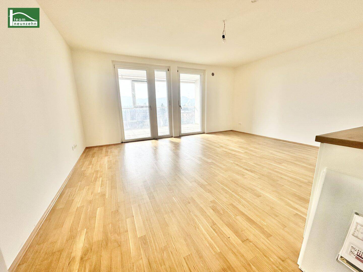 Geräumiger, heller Raum mit großen Fenstertüren und Zugang zu einem Außenbereich.