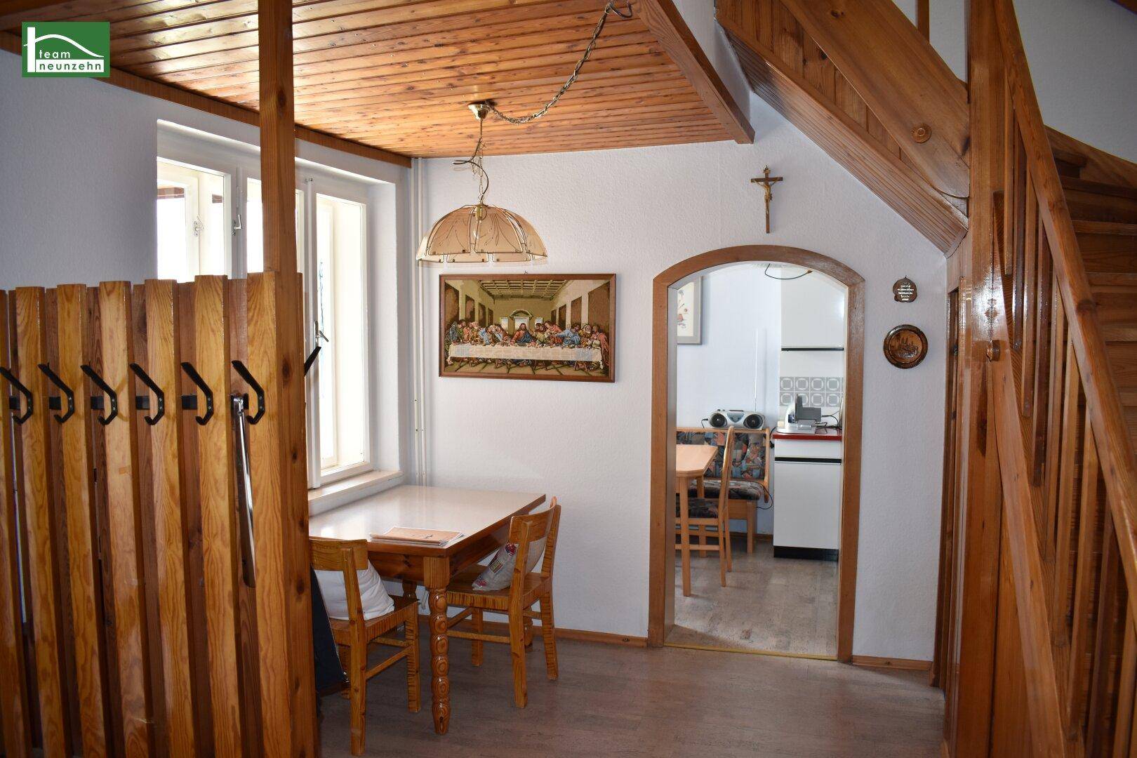Rustikaler Eingangsbereich mit Holzboden, Holzvertäfelung und Zugang zu weiteren Räumen und Treppe.