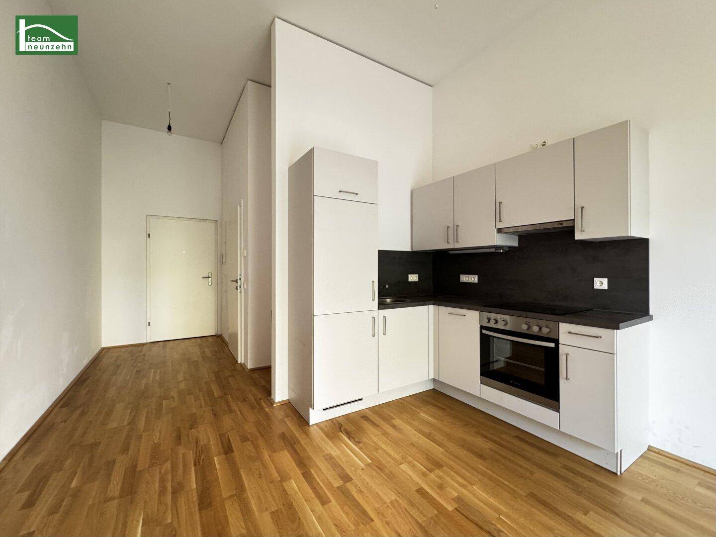 Offener Wohnbereich mit kompakter Küchenzeile und Holzboden, ideal für Singles oder Paare.