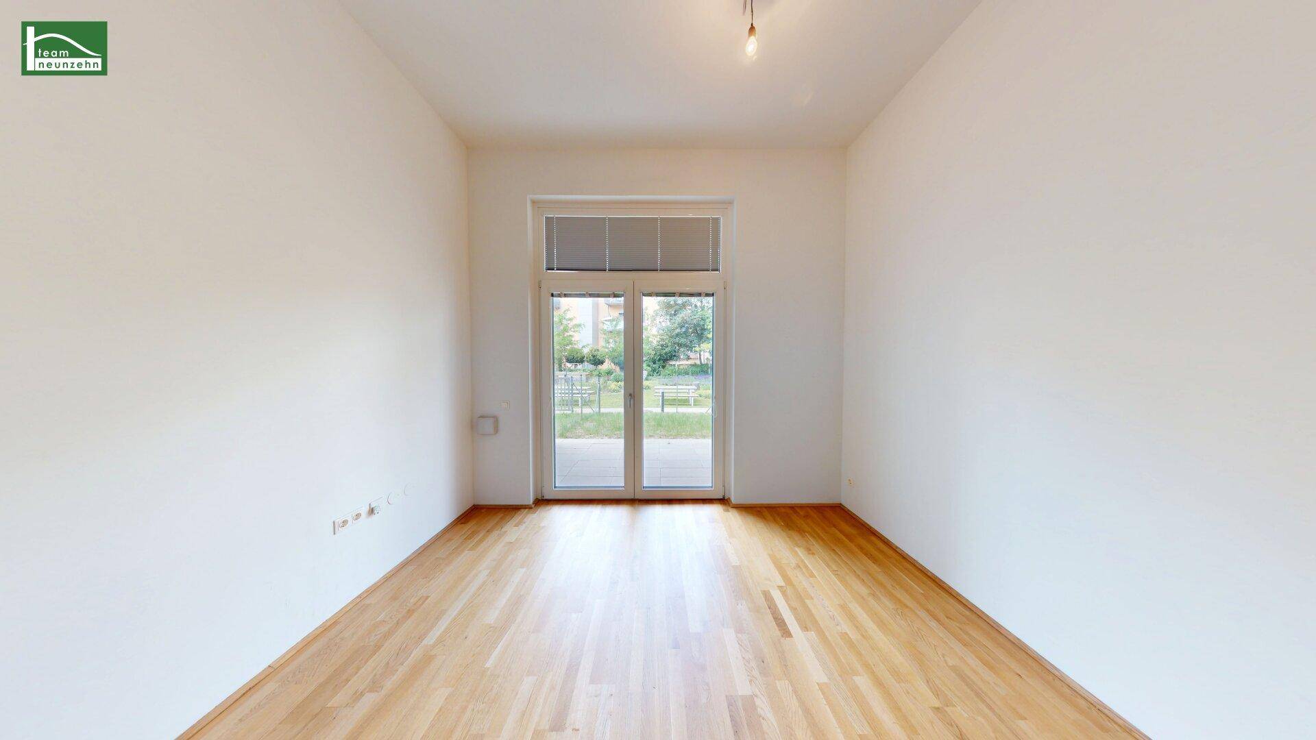 Heller, leerer Raum mit Holzboden und bodentiefen Fenstern, ideal für individuelle Gestaltung.