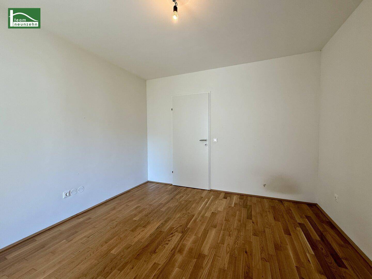 Leeres Zimmer mit Holzboden und weiß gestrichenen Wänden, ideal als Schlaf- oder Arbeitszimmer.