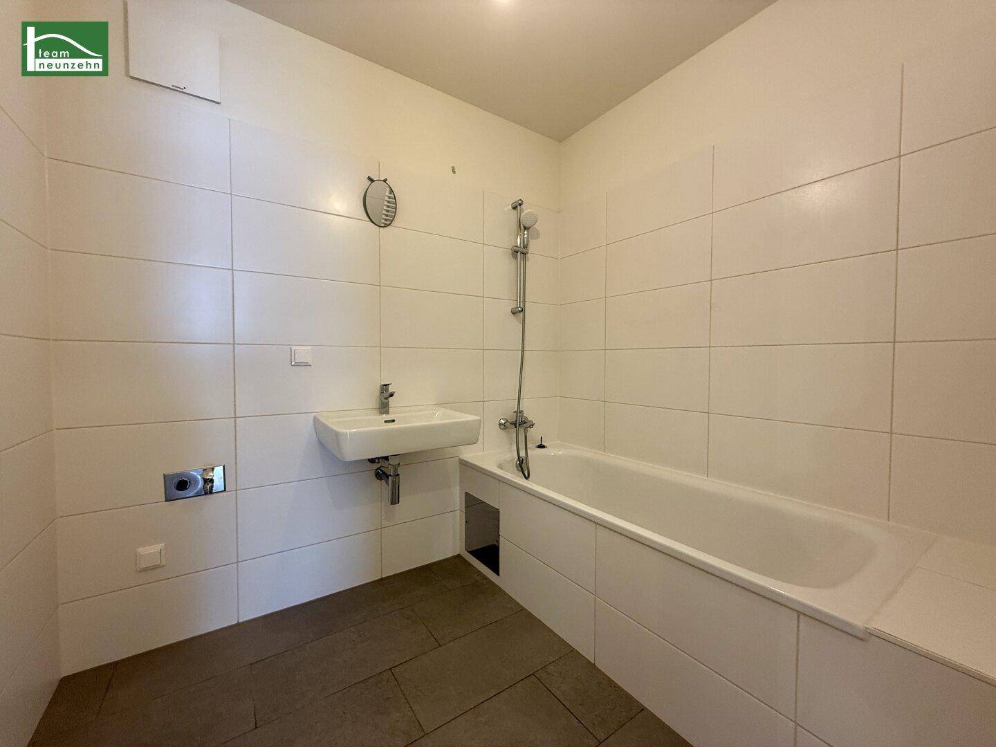 Modernes Badezimmer mit Badewanne, Dusche und weißen Fliesen an den Wänden.