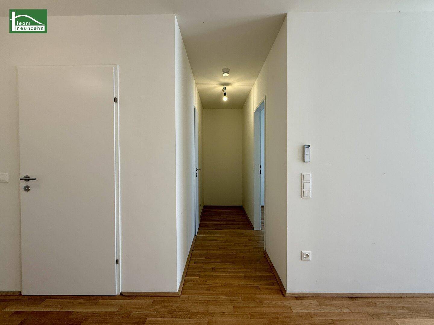 Heller Flur mit Holzboden und mehreren Türen, der zu den verschiedenen Räumen führt.