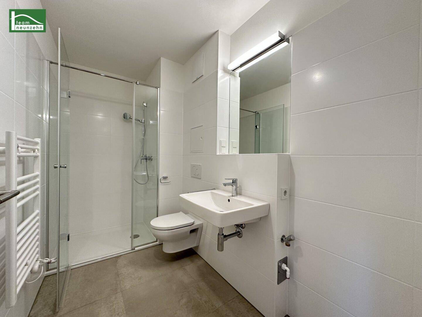 Modernes Badezimmer mit weiß gefliesten Wänden, ebenerdiger Dusche und Wand-WC.