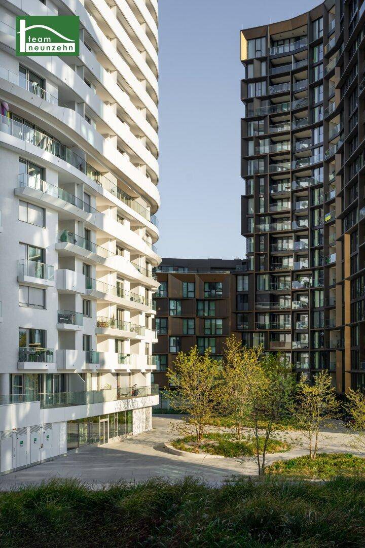 Moderne Wohngebäude mit geschwungenen Fassaden und einem begrünten Innenhof in urbaner Umgebung.