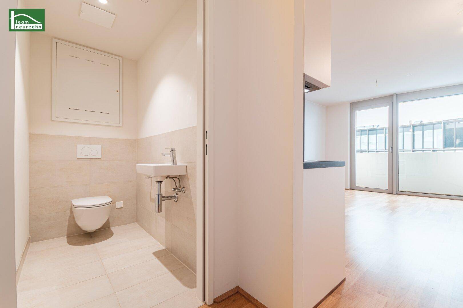 Modernes Gäste-WC mit Wand-WC, kleinem Waschbecken und hellen Fliesen.