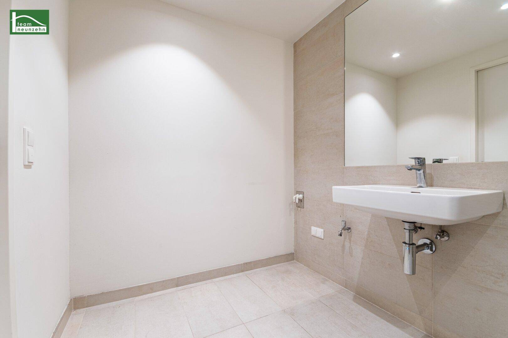 Geräumiges Badezimmer mit modernem Waschbecken und großem Wandspiegel, in neutralen Farben gehalten.