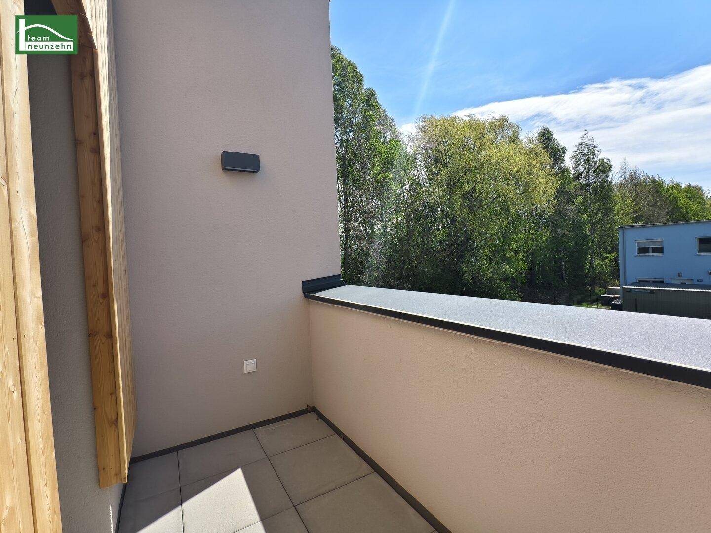 Kleiner Balkon mit Fliesenboden, Holzsichtschutz und sonnigem Blick ins Grüne.