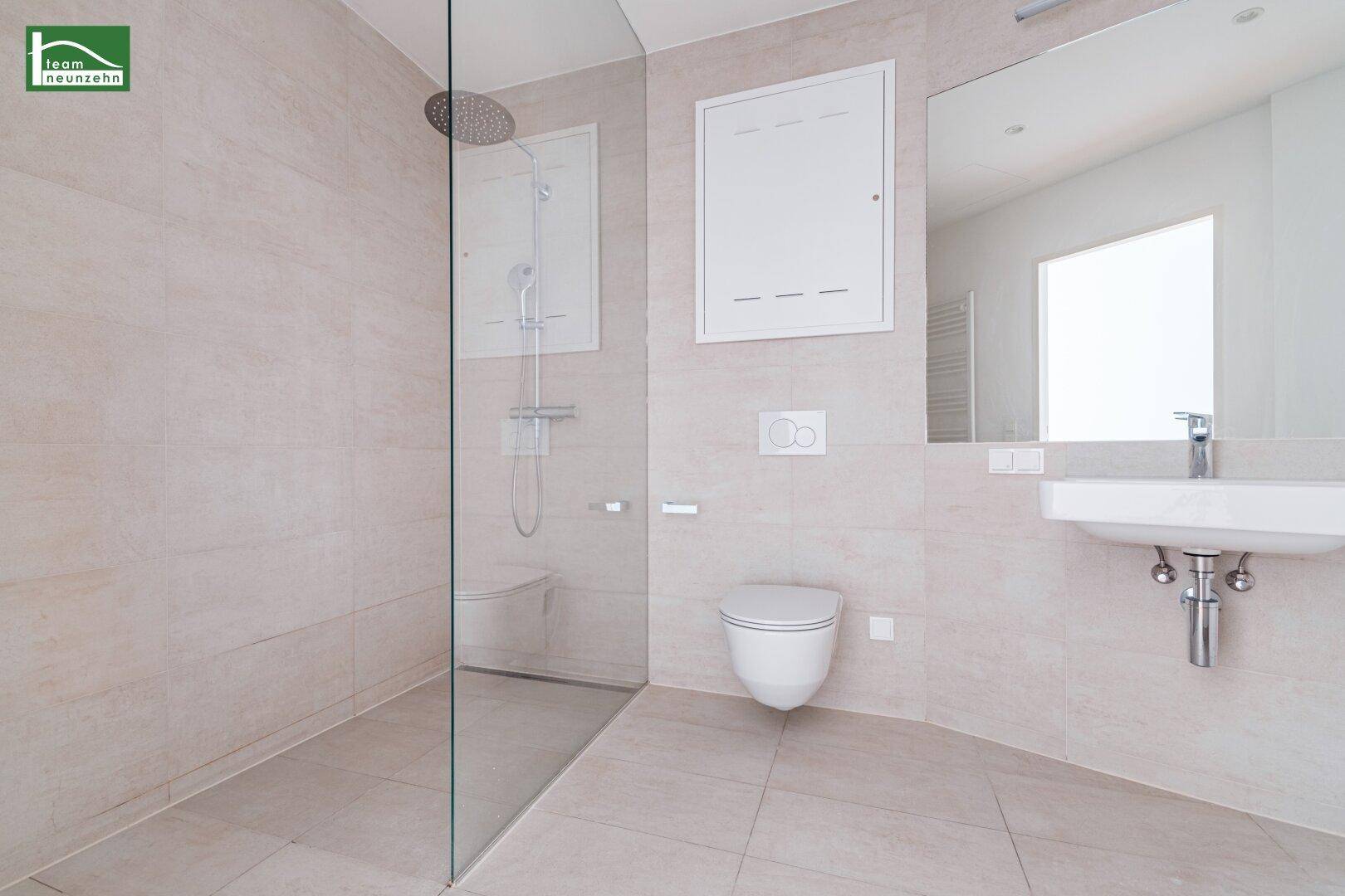 Modernes Badezimmer mit begehbarer Dusche, wandhängendem WC und hellem Fliesenboden.