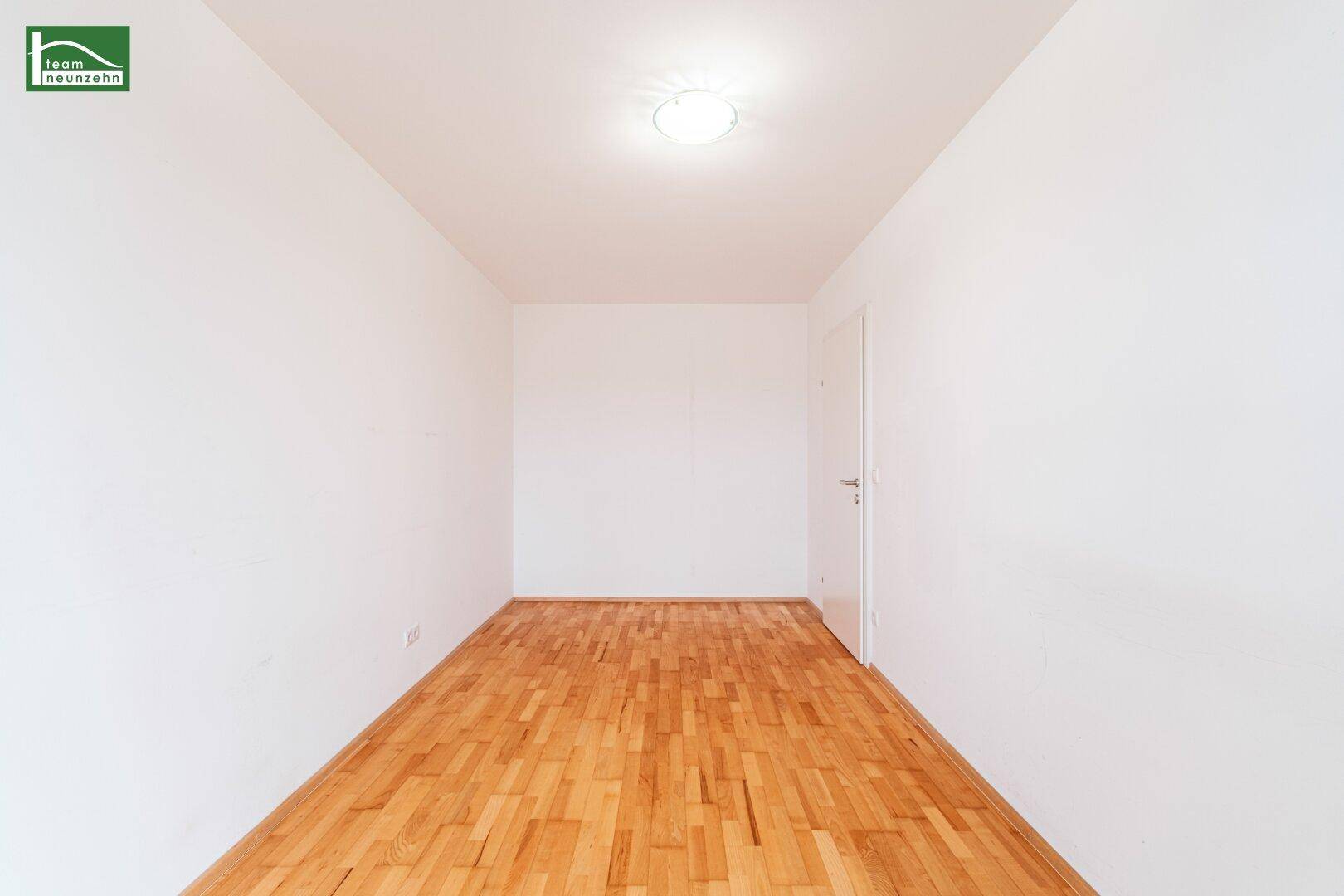 Leeres Schlafzimmer mit Parkettboden und weiß gestrichenen Wänden, bereit zur persönlichen Gestaltung.