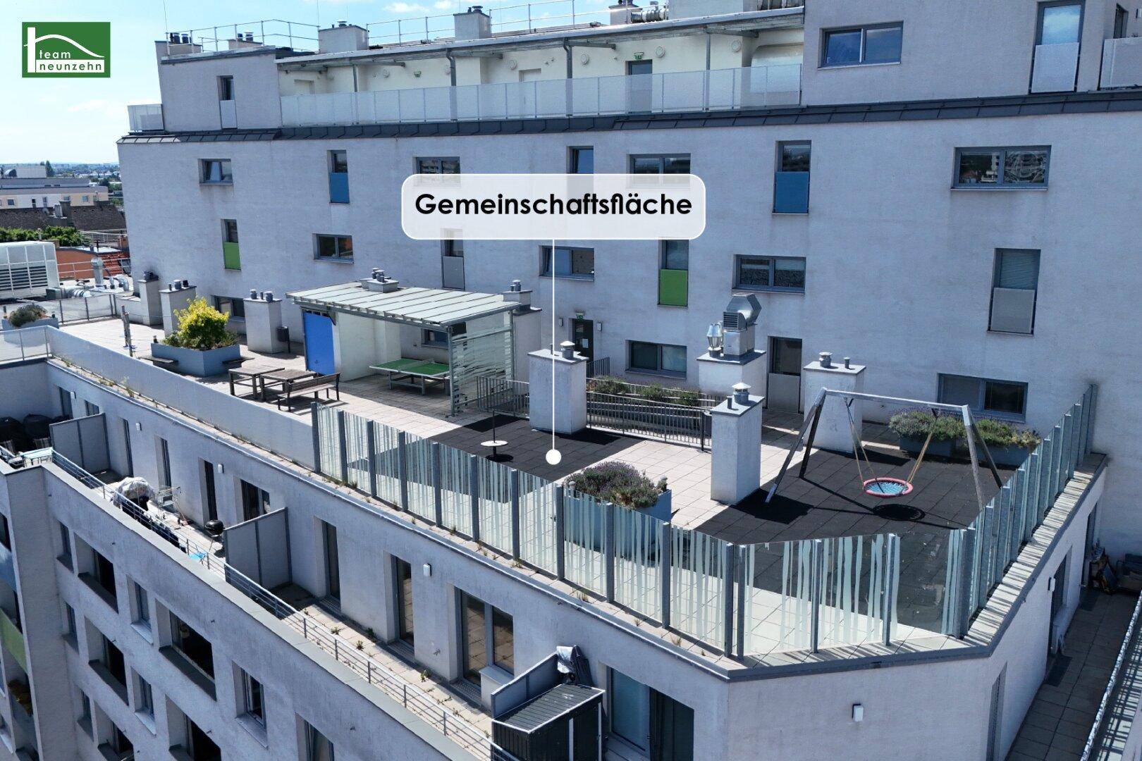 Dachterrasse mit Gemeinschaftsfläche, Sitzgelegenheiten und Spielgeräten auf dem Gebäude.