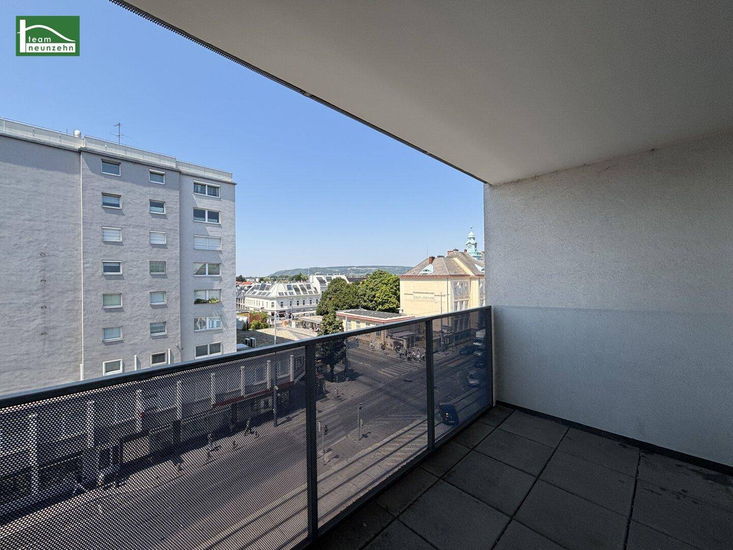 Geräumiger Balkon mit Fliesenboden und Metallgeländer, bietet einen weiten Blick über die Stadt.
