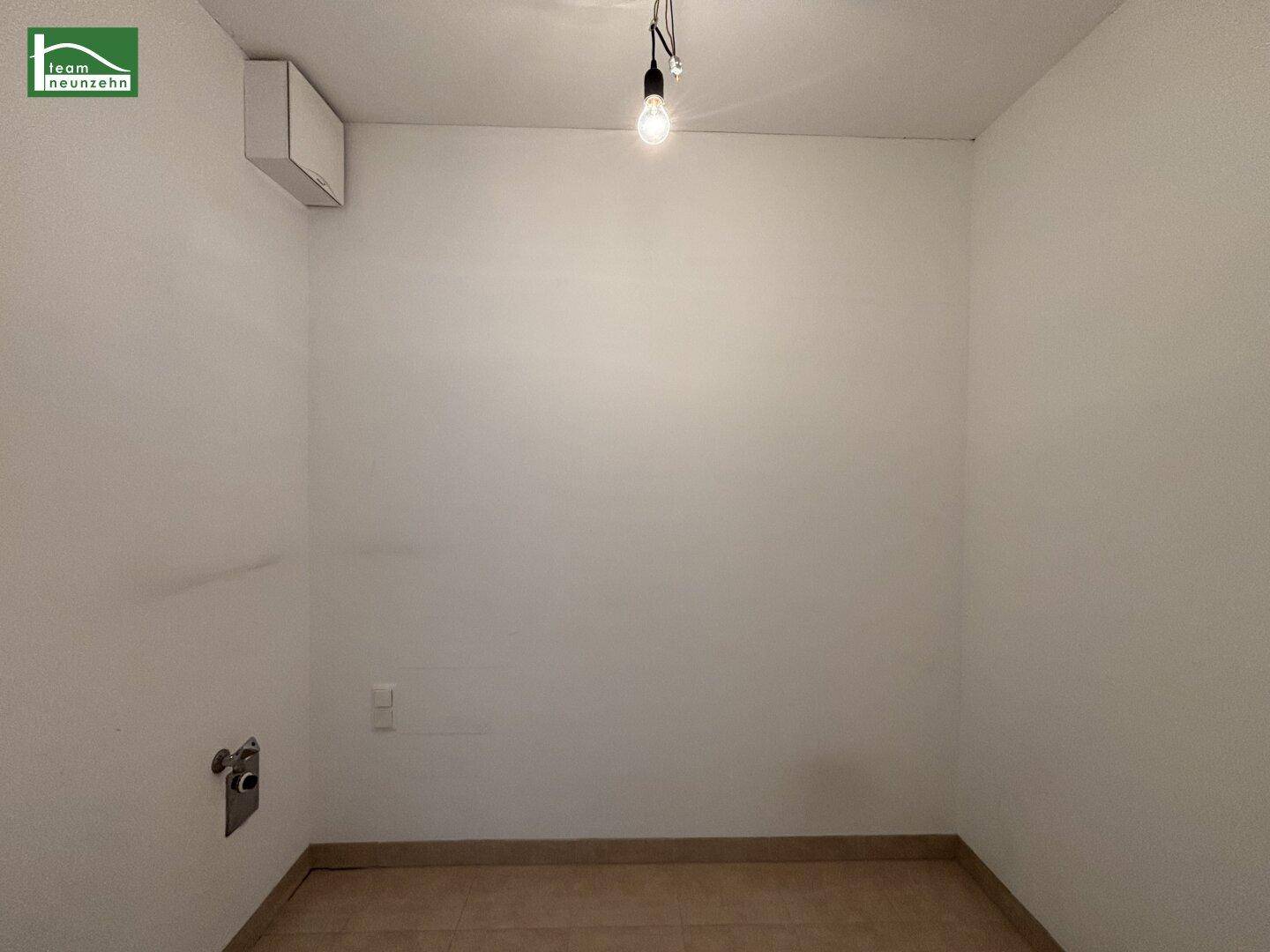 Leerer Hauswirtschaftsraum mit Fliesenboden und Anschlüssen, ideal für Waschmaschine und Trockner.