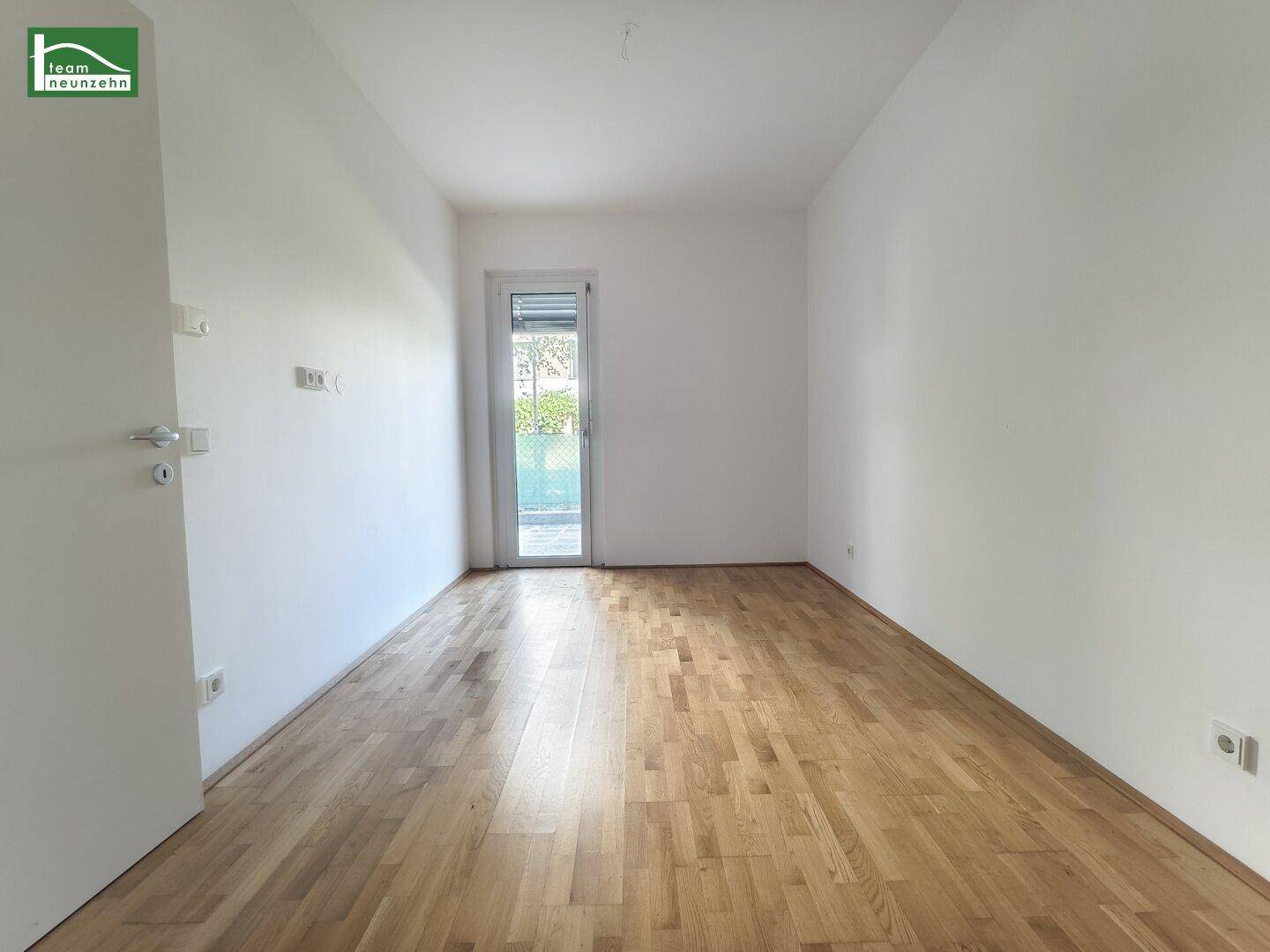 Ruhiges Zimmer mit Eichenparkettboden und Zugang zu einem Außenbereich.