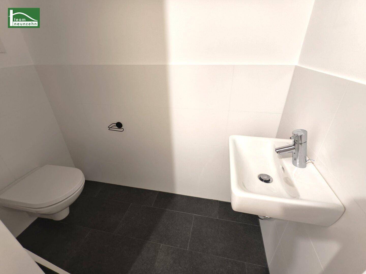 Separates Gäste-WC mit Wand-WC und kleinem Handwaschbecken.