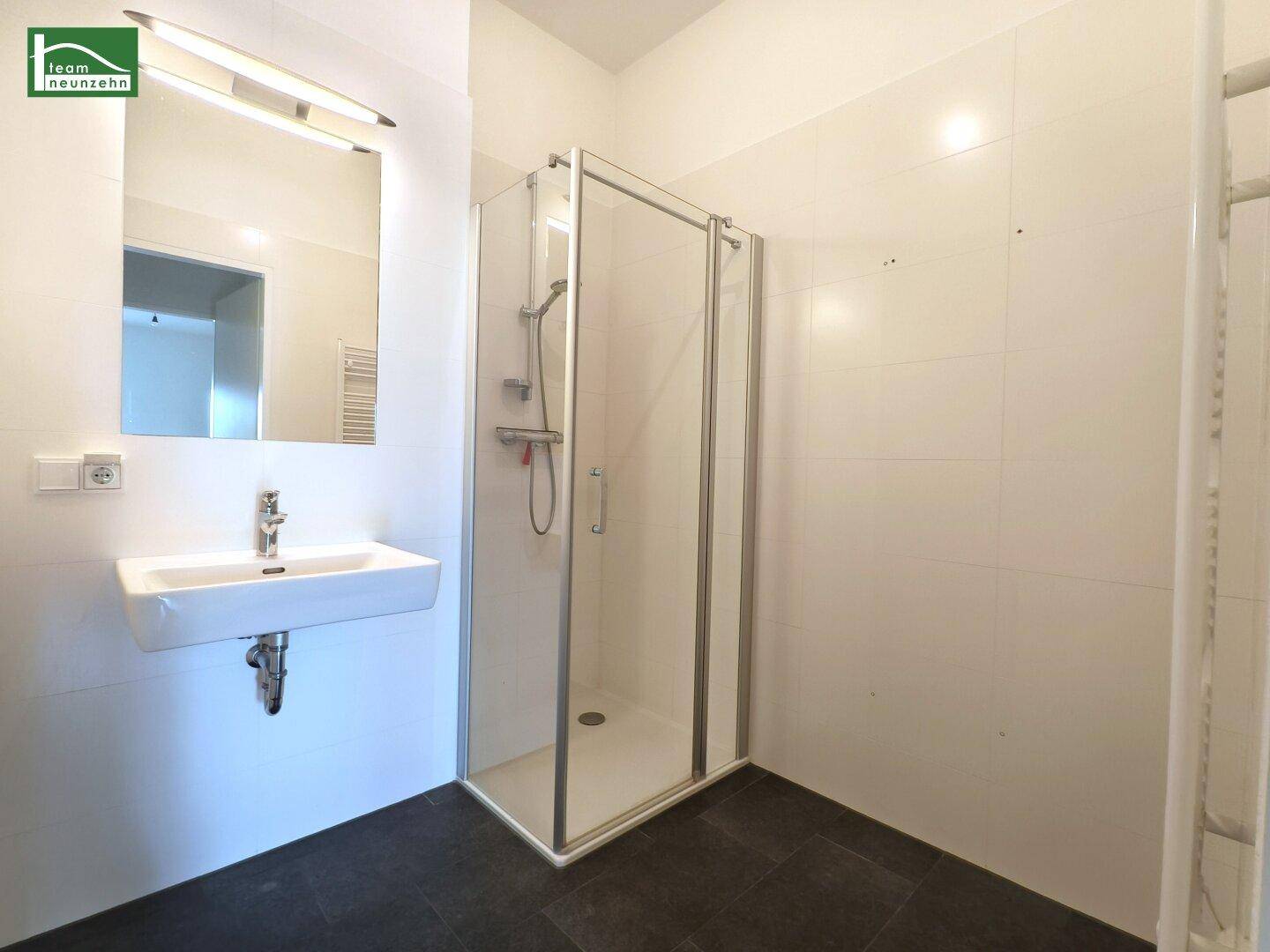 Modernes Badezimmer mit Duschkabine, Einzelwaschbecken und großem Spiegel.