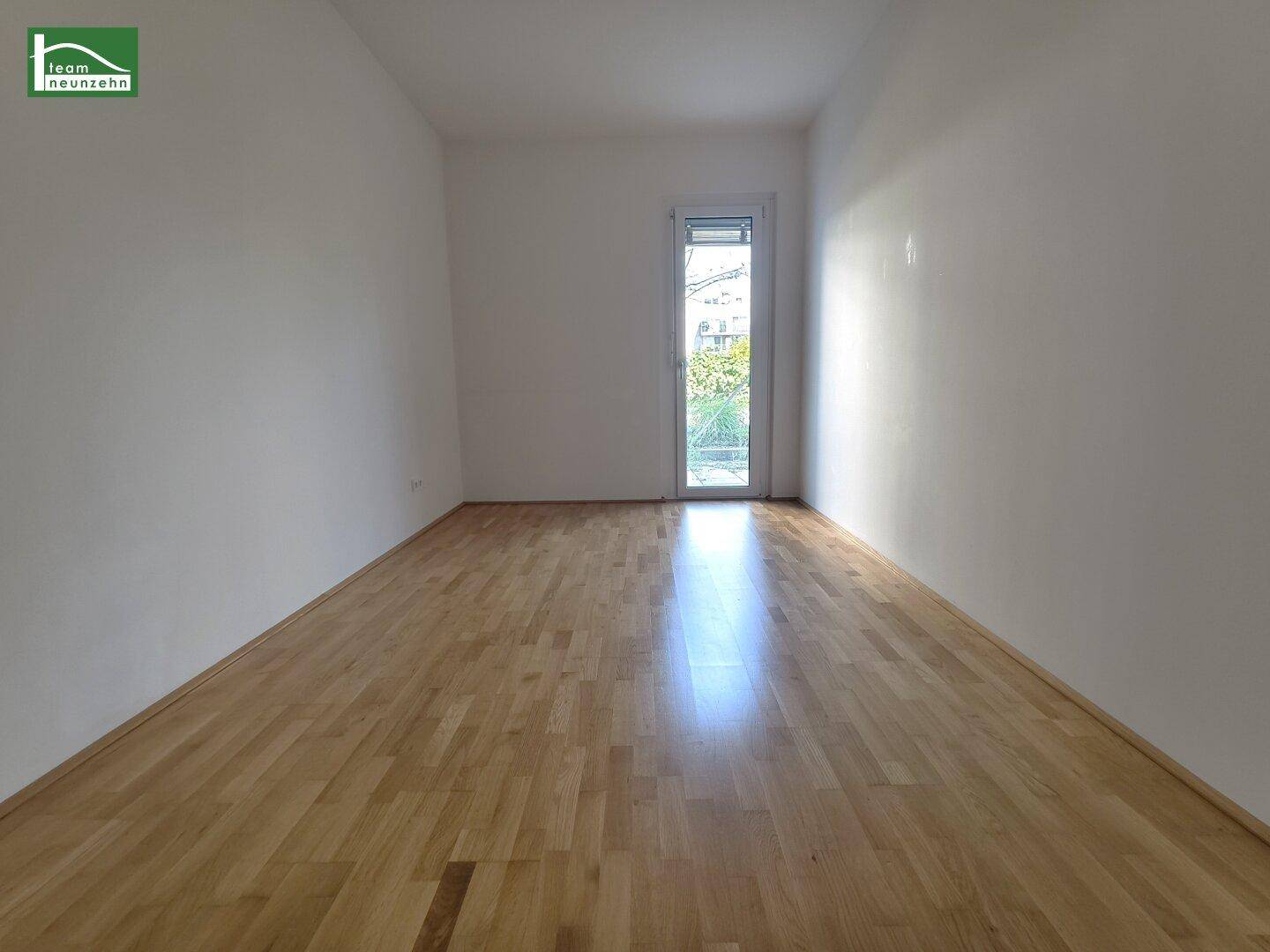 Helles Schlafzimmer mit Holzboden und Zugang zu einem kleinen Außenbereich.