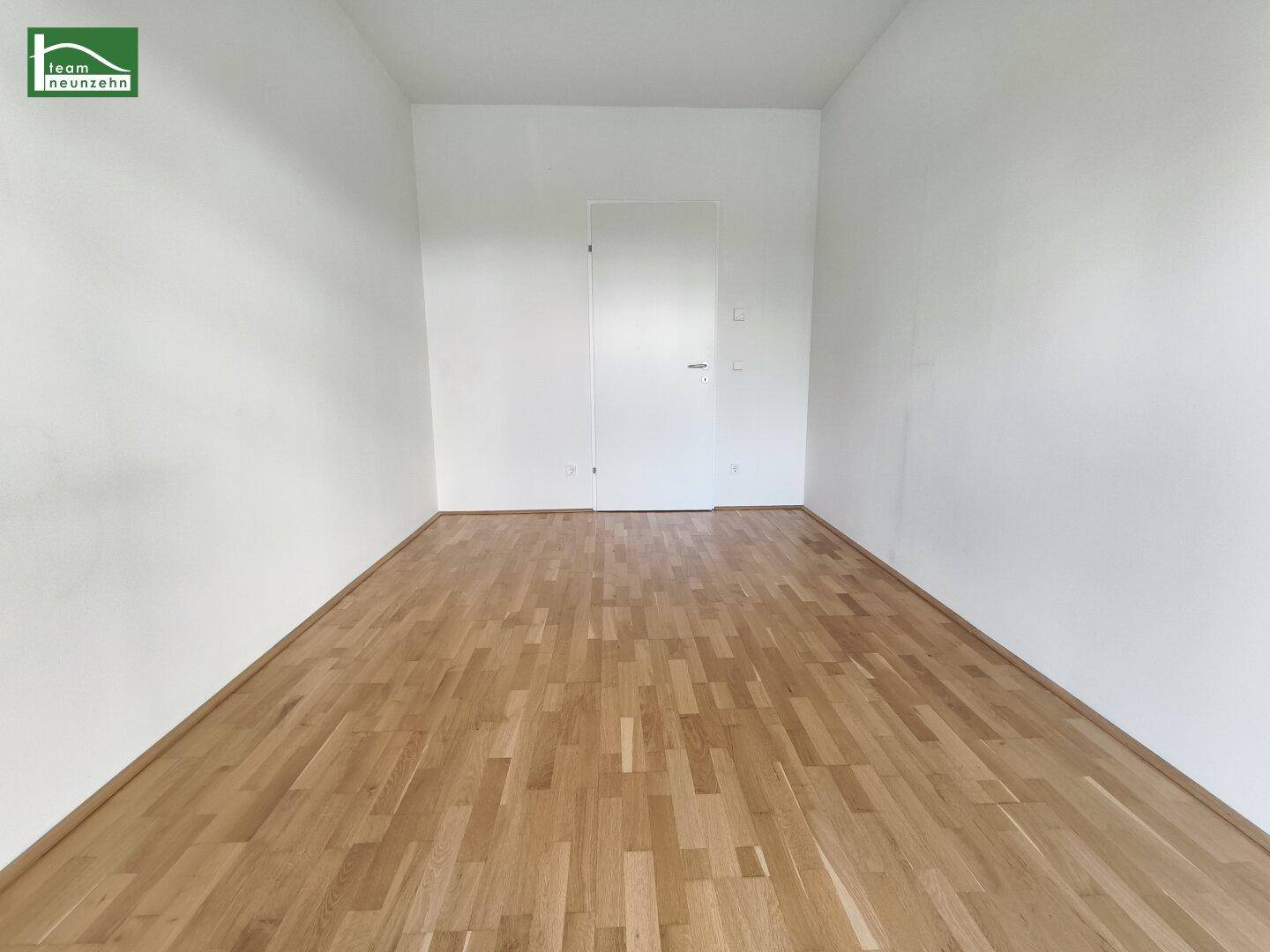 Leeres Schlafzimmer mit Holzboden und weiß gestrichenen Wänden.