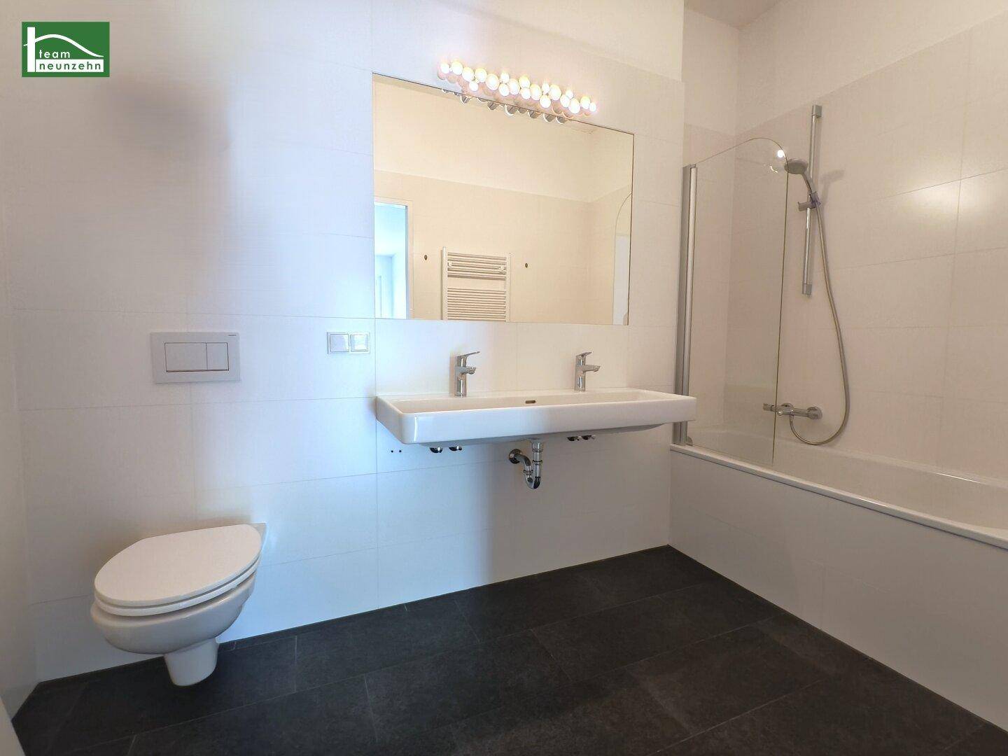 Modernes Badezimmer mit Badewanne, Doppelwaschbecken und Wand-WC.