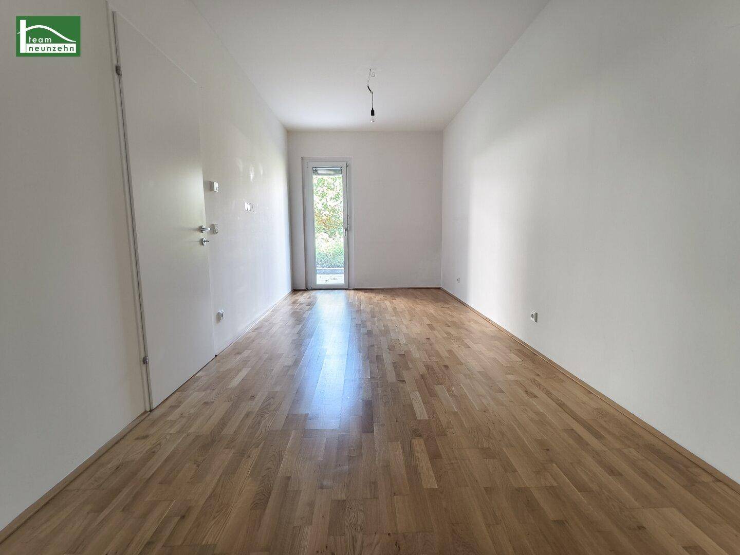 Leeres Schlafzimmer mit Holzboden und Zugang zu einem Außenbereich.