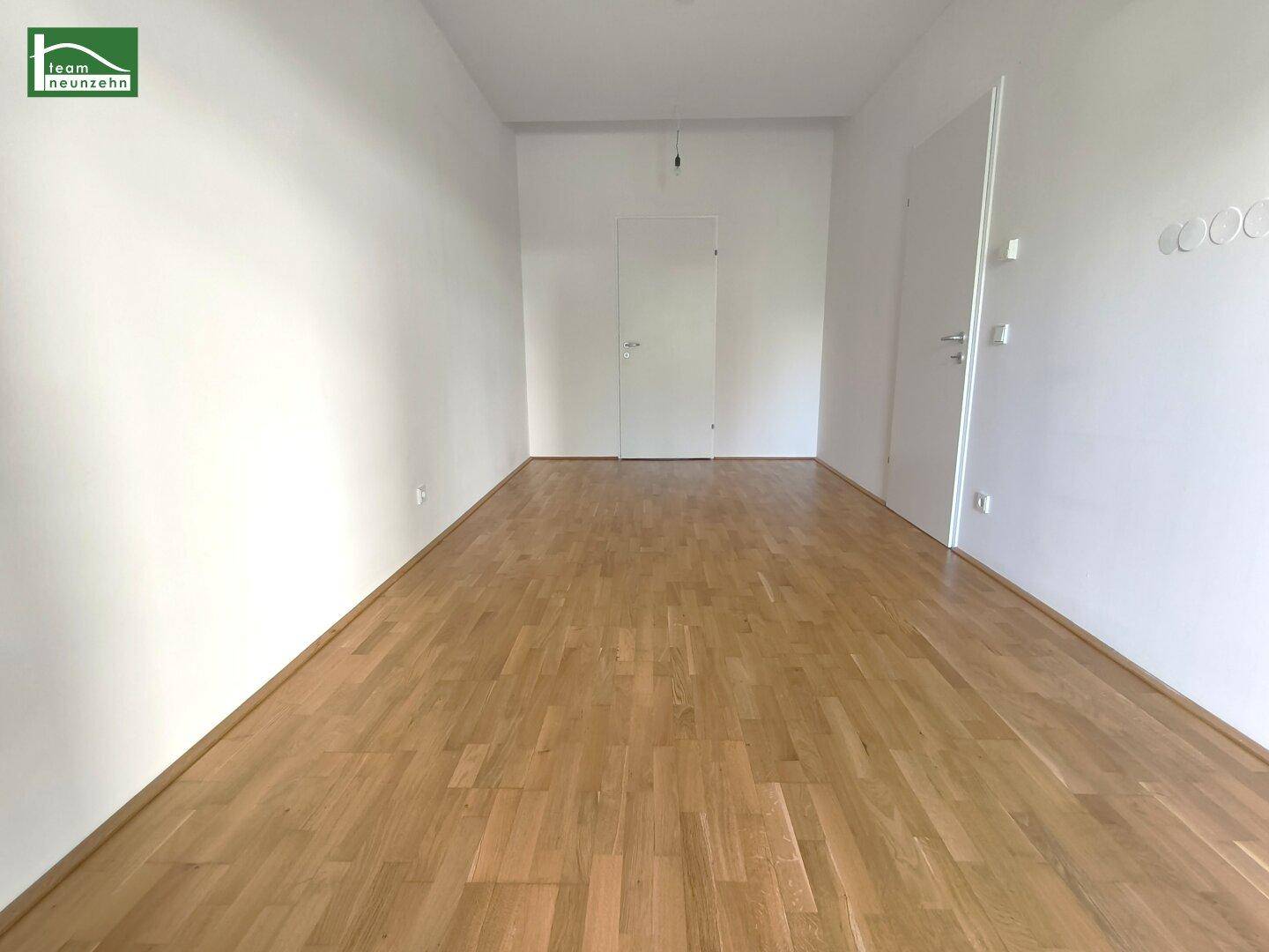Heller Flur mit Holzboden und weißen Wänden, bereit für die individuelle Gestaltung.