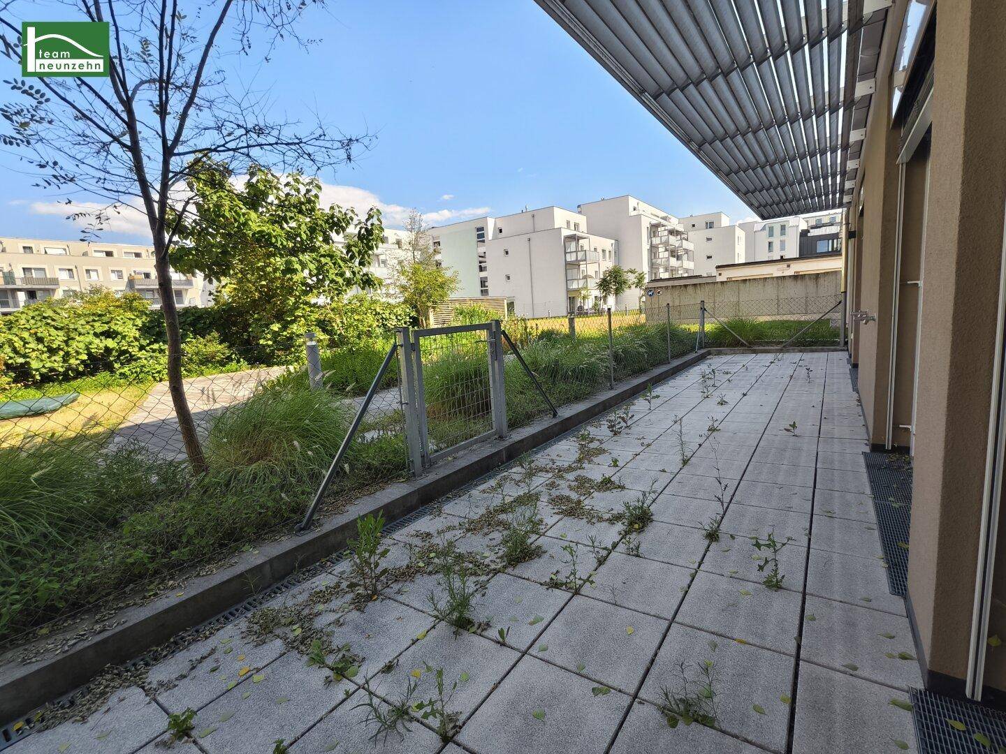 Große gepflasterte Terrasse mit Blick auf die umliegenden Wohngebäude und viel Grün.