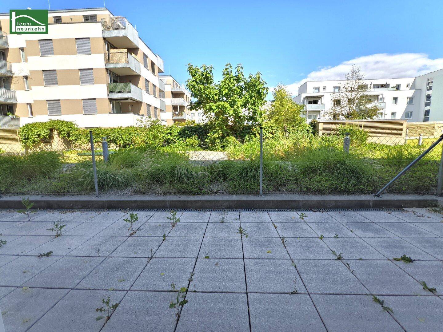 Gepflasterte Terrasse mit Blick auf die begrünte Umgebung und moderne Wohngebäude.
