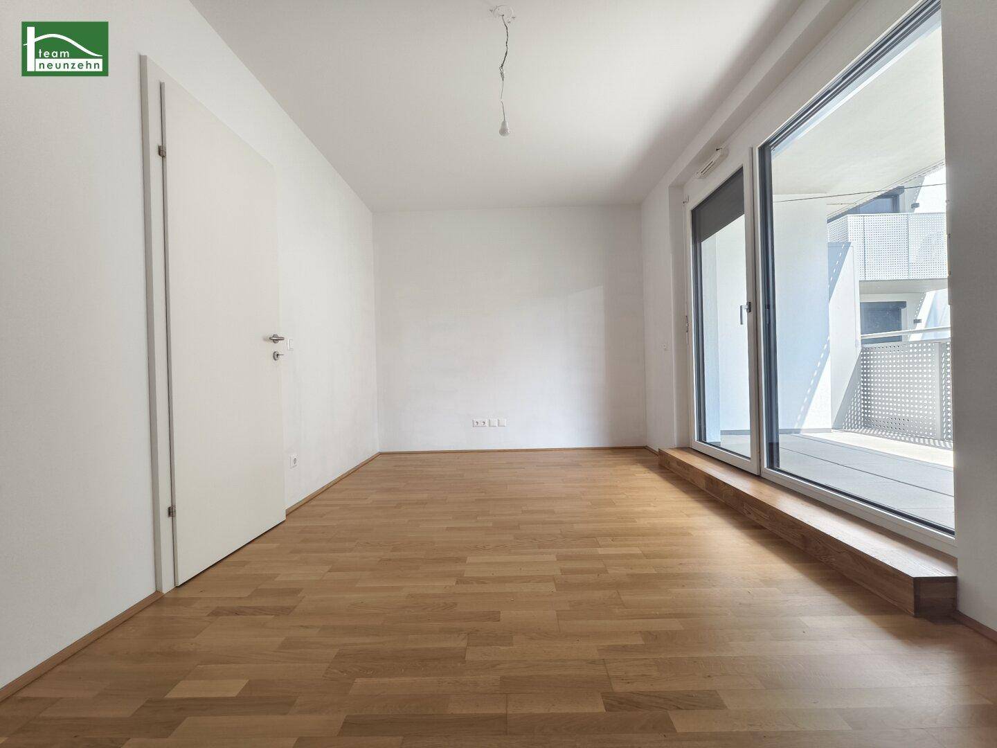 Geräumiges Schlafzimmer mit Parkettboden und großen Fenstern zum Außenbereich.
