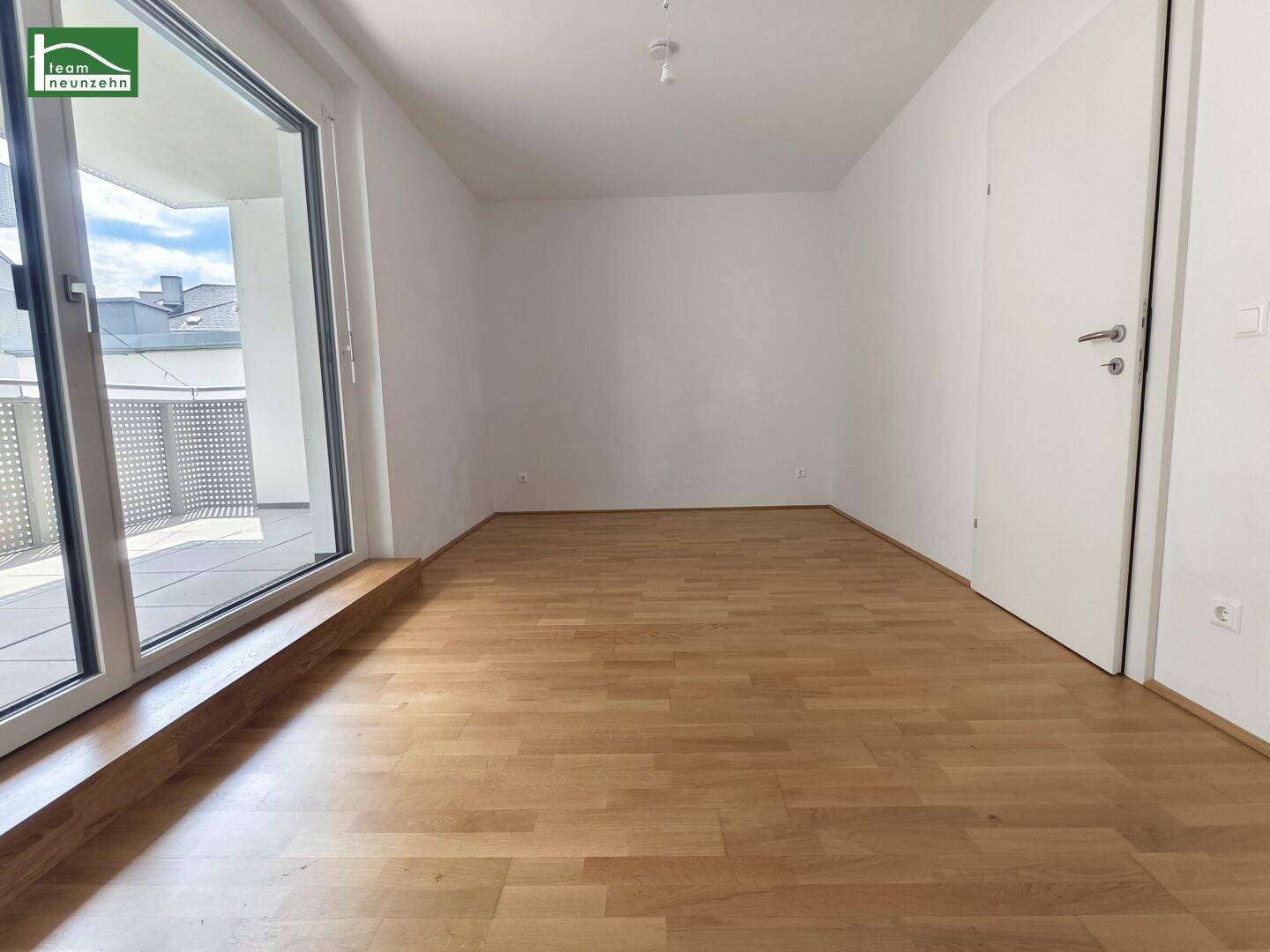 Helles Schlafzimmer mit Parkettboden und Zugang zu einem Balkon oder einer Loggia.