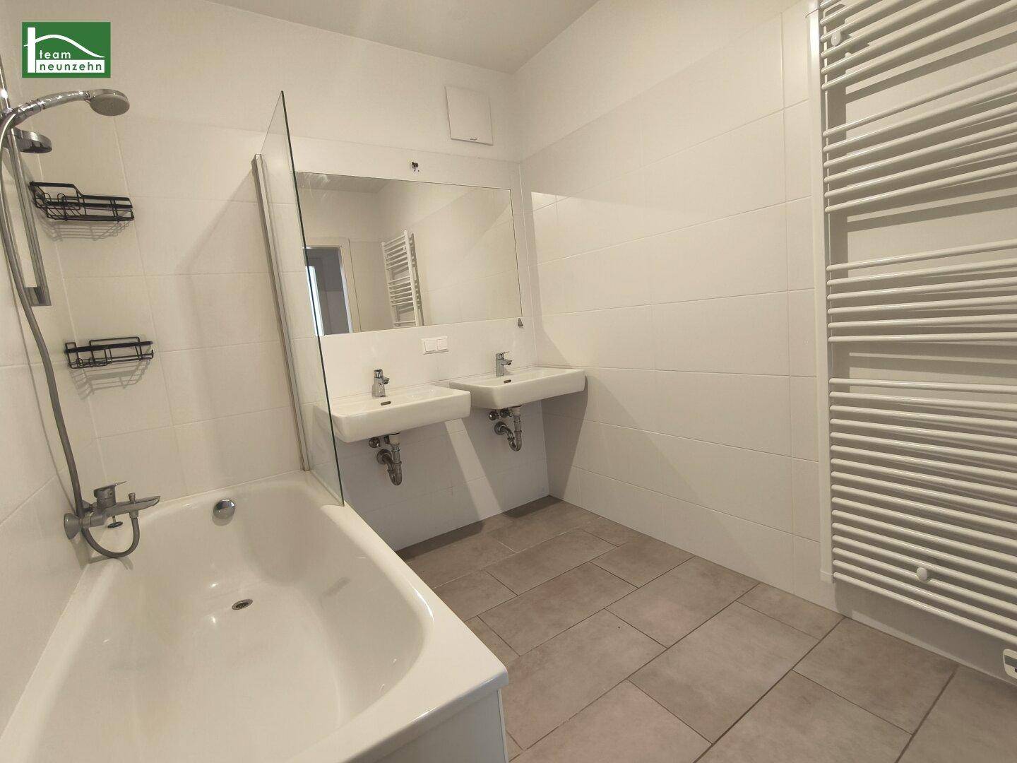 Modernes Badezimmer mit Badewanne, Doppelwaschbecken und beheiztem Handtuchhalter.