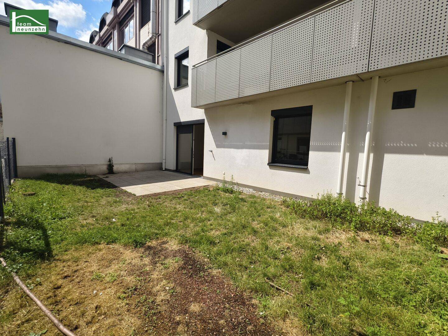 Kleiner Gartenbereich mit Terrasse und Blick auf die moderne Gebäudefassade.