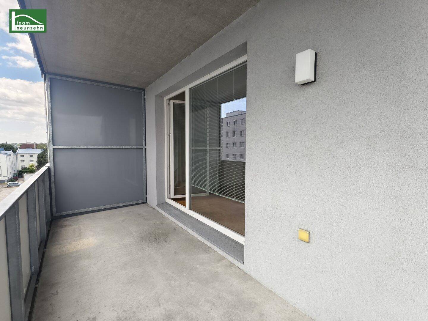 Balkon mit Schiebetürzugang zum Innenbereich und Blick auf die Nachbarschaft.