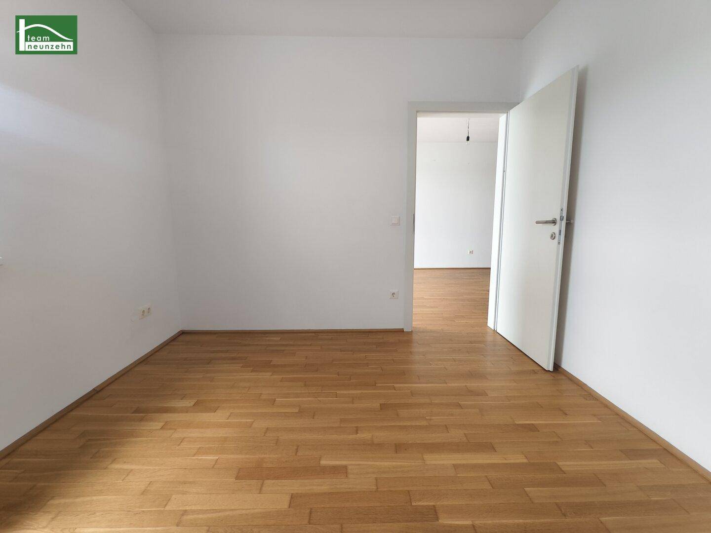 Leeres Zimmer mit Holzboden und weiß gestrichenen Wänden, bereit zur Einrichtung.