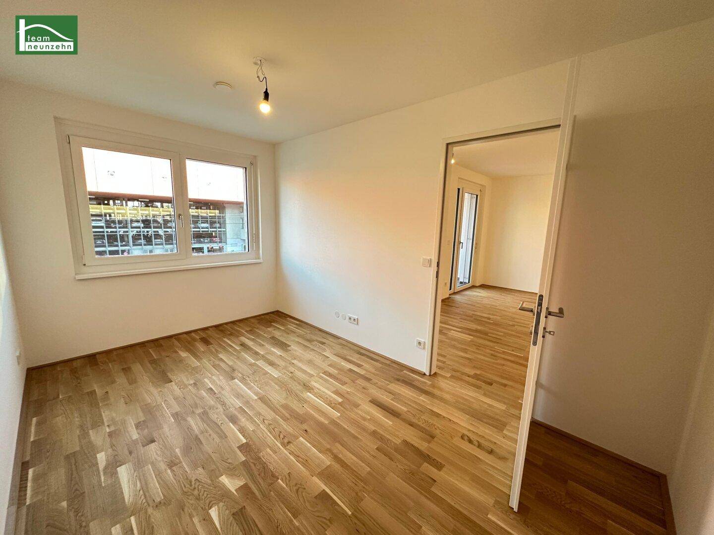 Leeres Zimmer mit Holzboden und Fenster, ideal als Schlaf- oder Arbeitszimmer.