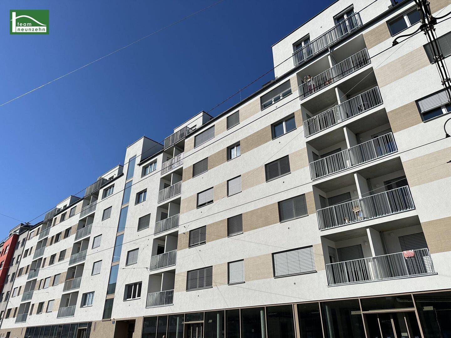 Moderne Fassade eines Mehrfamilienhauses mit zahlreichen Balkonen und großen Fenstern.