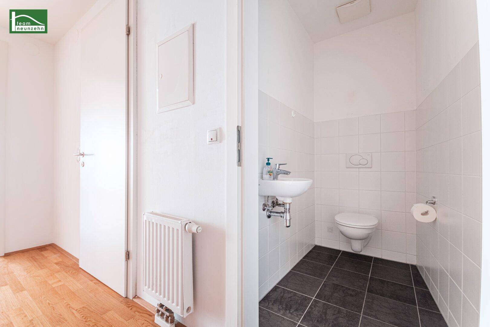 Separates Gäste-WC mit Waschbecken und Toilette, ausgestattet mit weißen Fliesen.