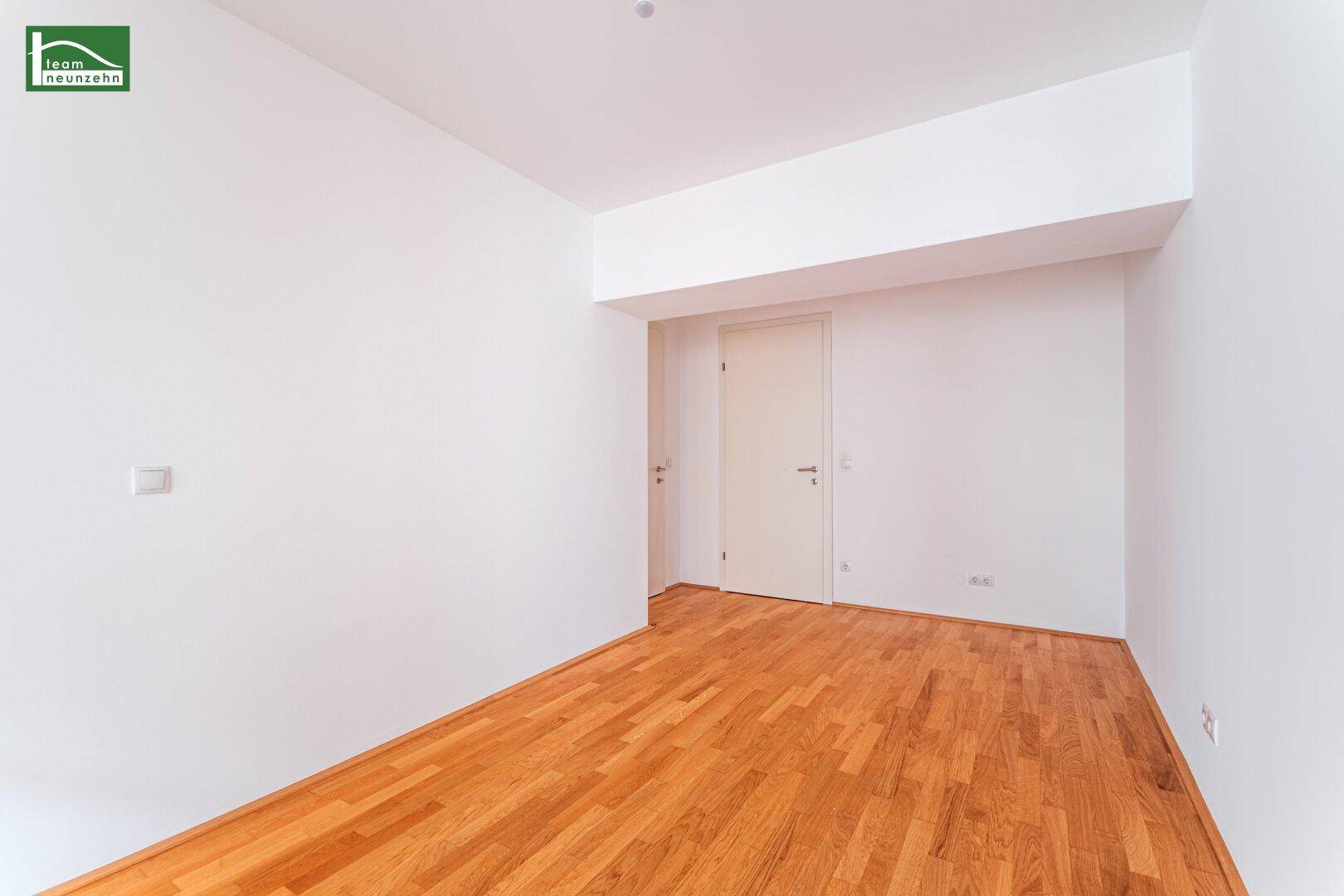 Leerer Raum mit hellem Holzboden und weißen Wänden, bereit zur individuellen Gestaltung.