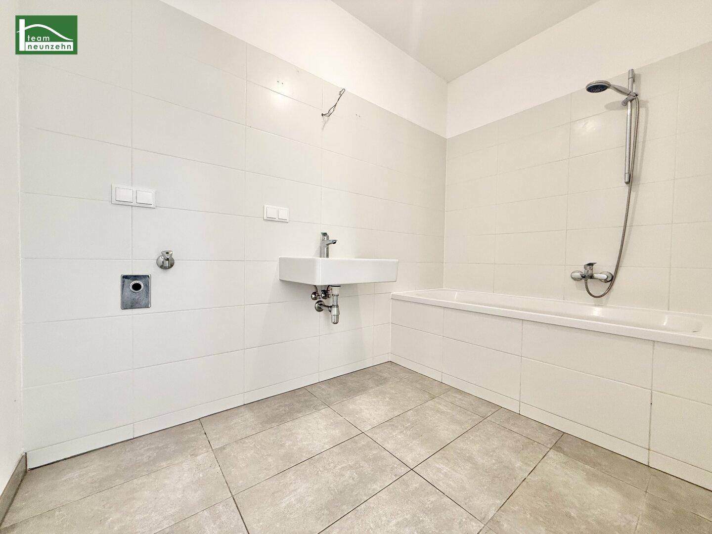 Modernes Badezimmer mit Badewanne, Dusche und Waschbecken, hell gefliest.